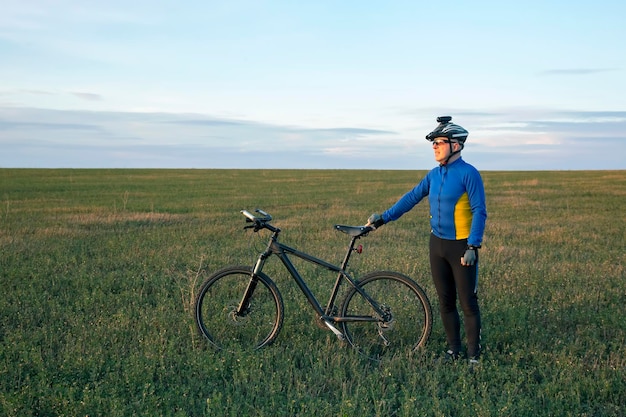 cyclist with Bicycle standing on field path