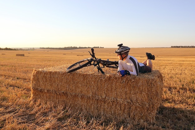 わらで収穫された畑で自転車を休ませているサイクリスト