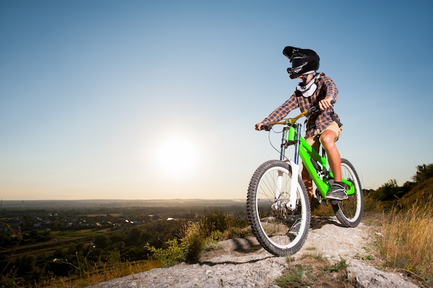 Cyclist with mountain bike on the hill under blue sky