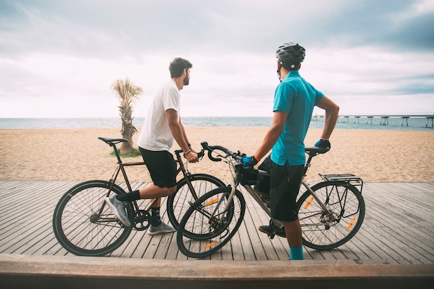 Cyclists on beach walkway looking out to the sea with bridge in background copyspace sport