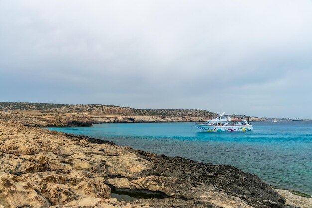 CYPRUS KAAP CAVO GRECO Toeristen zeilden op een schip de blauwe lagune in om te zwemmen