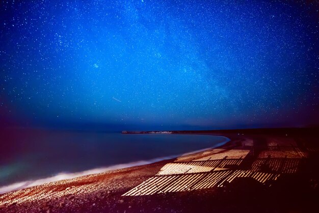 Cyprus-zomerlandschap met sterren aan de hemel en vreemde schaduwen op het strand, natuurlijke sterrenreisachtergrond