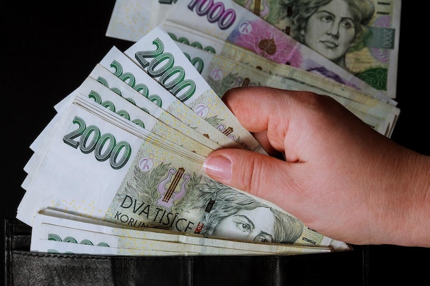 Photo czech money in the hands of a woman on a black background banknotes of 2000 woman counts money