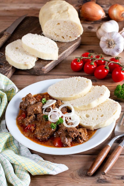 Czech traditional recipe for goulash with homemade dumpligs served in simple rustic style