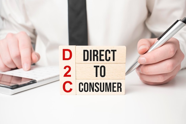 나무 블록에 쓰여진 D2C 단어 DirecttoConsumer 단어의 약어인 D2C는 노란색 테이블 비즈니스 개념 파란색 배경에 있는 나무 빌딩 블록으로 만들어집니다.