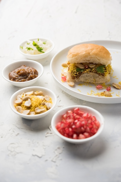 Dabeli is een Indiaas snackitem geserveerd met granaatappelpitjes en koriander in een witte keramische plaat. Het is een populair Navratri Festival-eten?