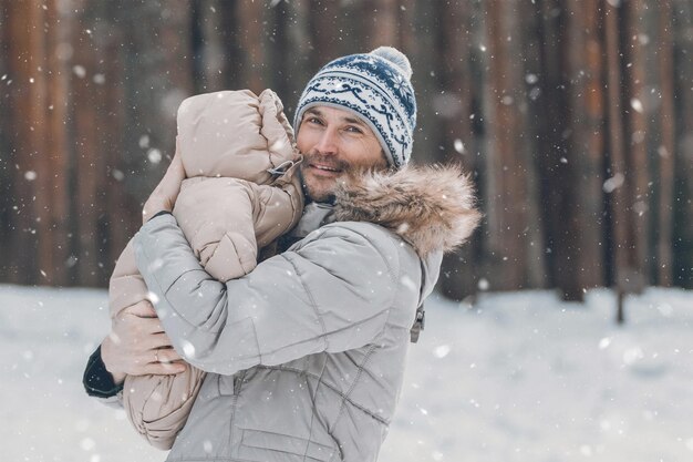 Dad and baby are walking along the forest Dad holds a baby in his arms in winter Dad and daughter outdoors in winter