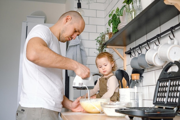 A dad and baby toddler cooking together A man mixing ingredients for dough using blender