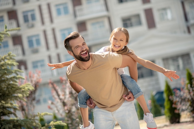 Dad carrying his cute daughter on his back