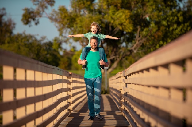 Dad and child having fun outdoors father giving son ride on back in park