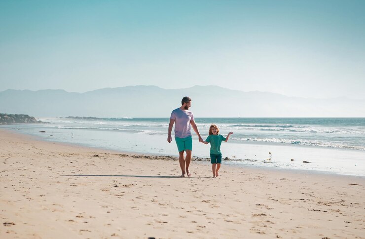 Dad and child having fun outdoors father and son walking on summer beach dad and child holding hands