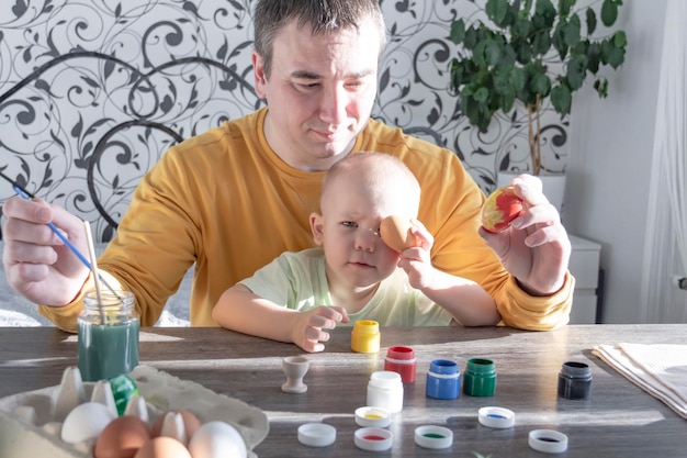 Dad and child paint eggs for Easter