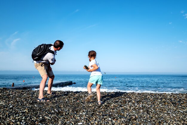 Foto papà e figlia stanno giocando in riva al mare. il concetto di una vacanza in comune con un bambino. festa del papà