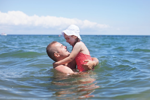 Foto papà e figlia che fanno il bagno, famiglia felice che riposa sul mare