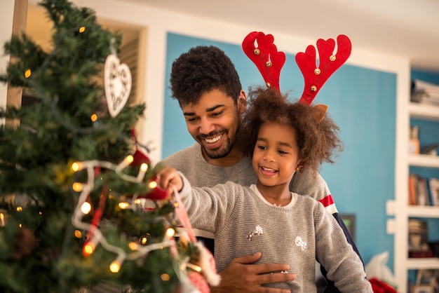 Dad and daughter decorating Christmas tree together