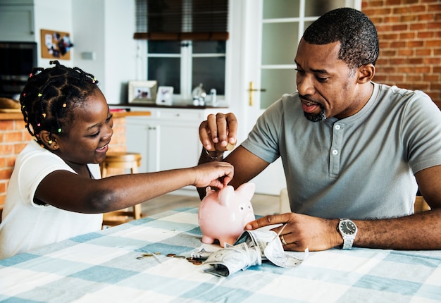 Dad and daughter saving money to piggy bank