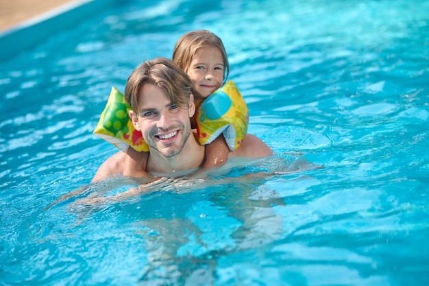 お父さんと娘が一緒にプールで泳いでいる