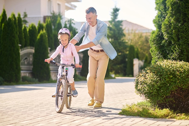 Dad helping his daughter learn riding a bike