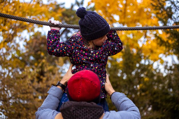 Dad helps daughter to walk on tightrope in autumn park