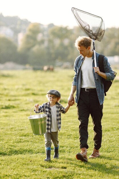 Dad and his child boy spend time outdoors together. Curly toddler boy wearing a plaid shirt and a hat