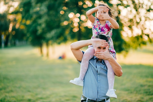 Dad holding his daughter on shoulders at nature.