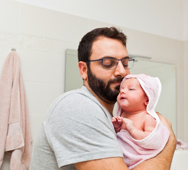 Dad holds his daughter in his arms after the first bath.