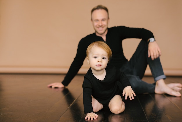 Dad holds a one-year-old daughter on a beige background. Fatherly love. Father's day