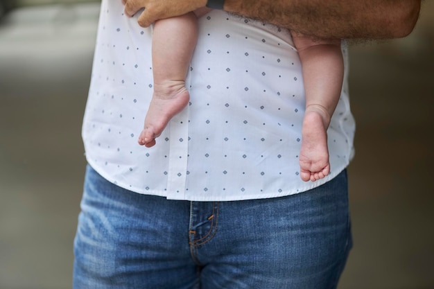 お父さんは小さな子供を腕に抱き、子供の足の画像をトリミングしました