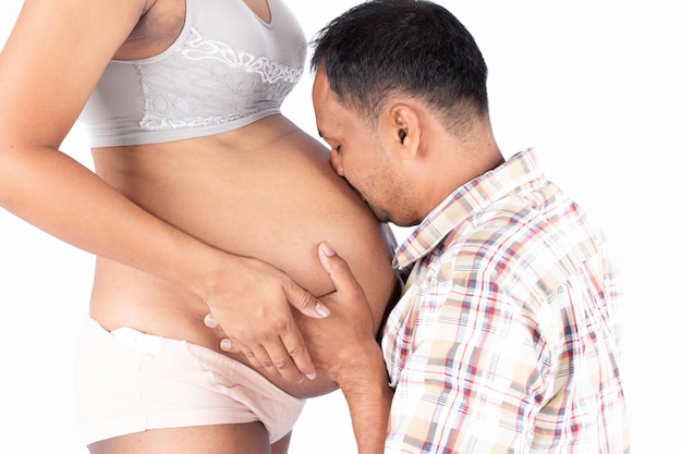Dad hugging and kissing on belly of pregnant wife