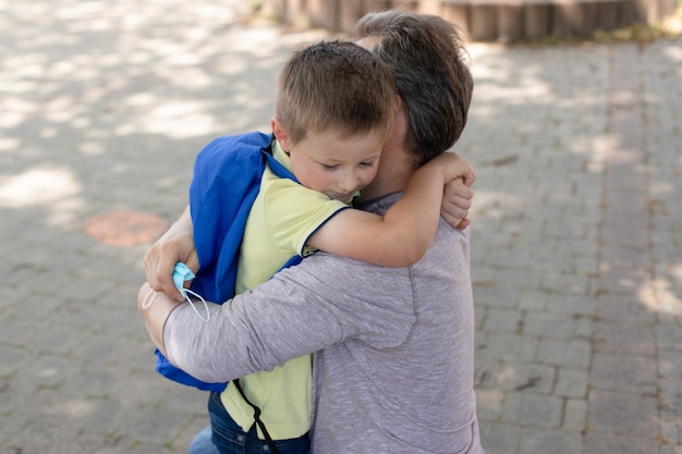 Foto papà abbraccia il figlio davanti alle porte della scuola o dell'asilo