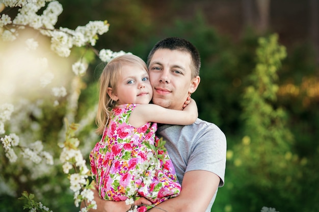Фото Папа в цветущем вишневом саду держит на руках свою любимую милую маленькую дочку 3 года