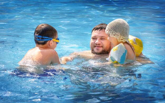 Papà e i bambini giocano insieme in piscina.