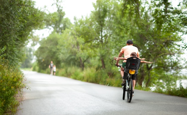 dad and kids ride in the drizzle on a bike. cycling with children