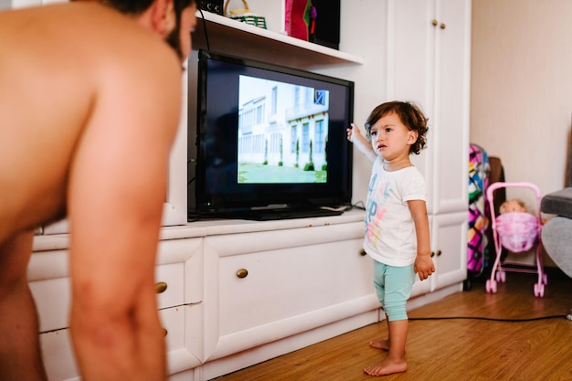 Dad looking TV and daughter crying in the room indoor in home Family portrait father dad prohibits girl watching TV concept of a family holiday Close up