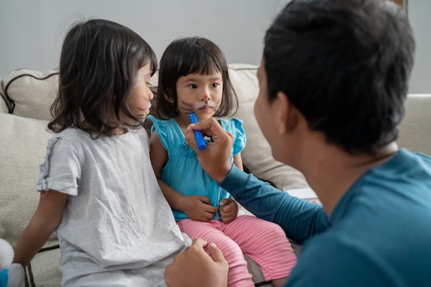 Dad making some face painting on daughter's faces