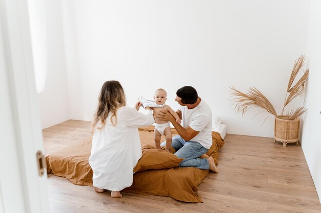 dad and mom are dressing the baby  he is not happy