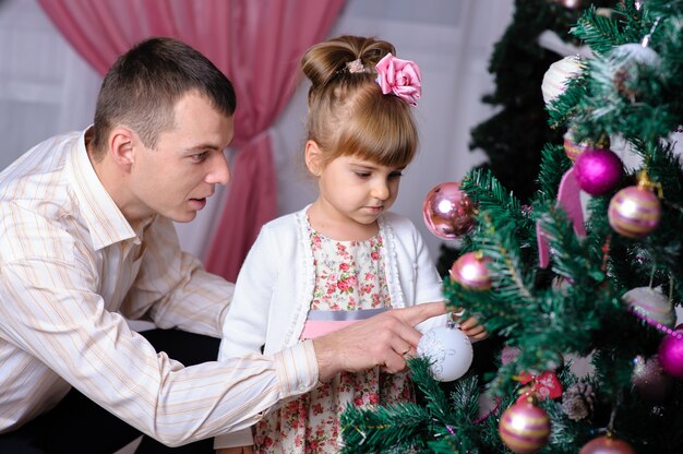 Dad, mom and daughter near the Christmas tree.