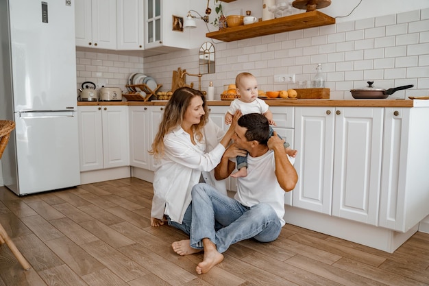 папа и мама играют с ребенком на полу в кухне