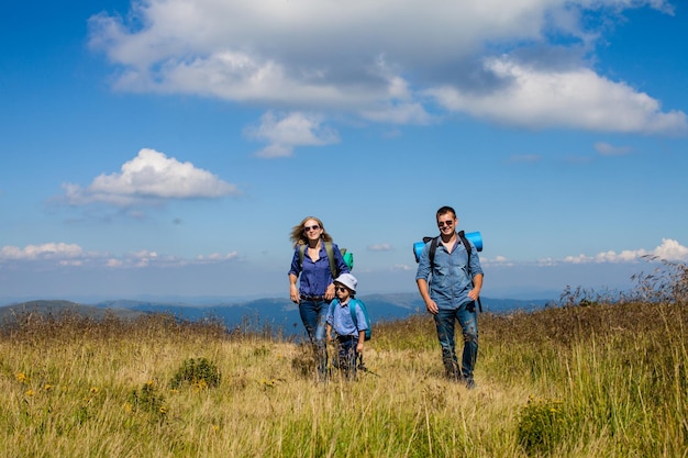 Dad, mom and son with backpacks travels in the mountains