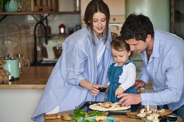 Dad mom and their daughter cook pizza together in the kitchen T