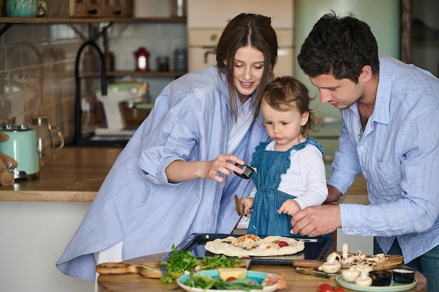 Dad mom and their daughter cook pizza together in the kitchen T