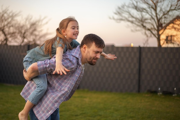 Dad playing with his daughter in the backyard of the house