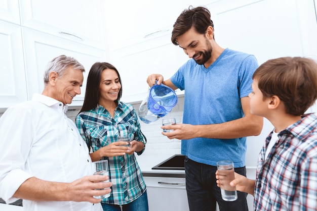 Dad pours the whole family water from the filter.