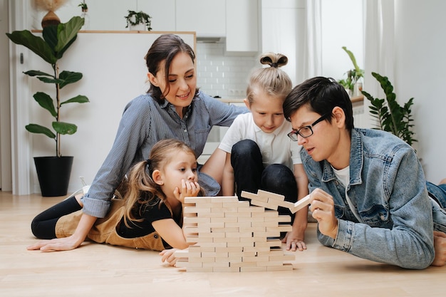 Dad ruining jenga wall family playing on the floor pulling tiles