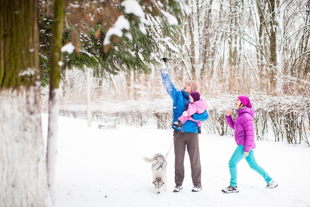 The dad showing his adorable little daughter a snowfall, winter snowy day