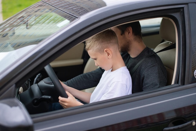 dad shows his little son how to drive a car