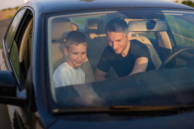 Dad shows his little son how to drive a car