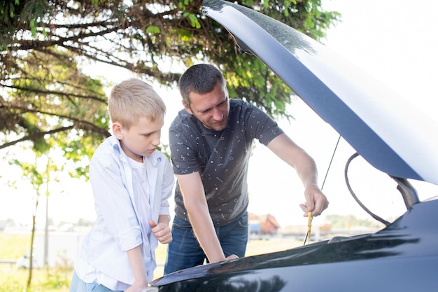 Dad shows his son how the machine works Open the hood of the car