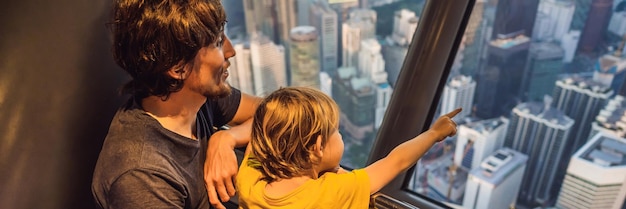 Dad and son are looking at kuala lumpur cityscape panoramic view of kuala lumpur city skyline