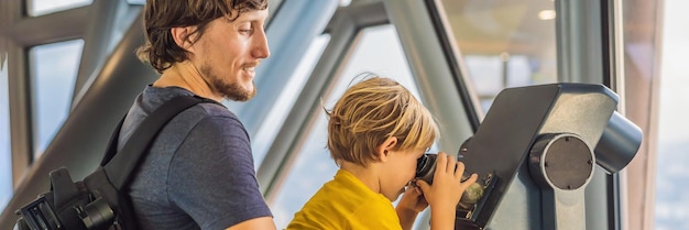 Dad and son are looking at kuala lumpur cityscape use binoculars panoramic view of kuala lumpur city